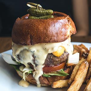 very thick, juicy hamburger with french fries on a plate