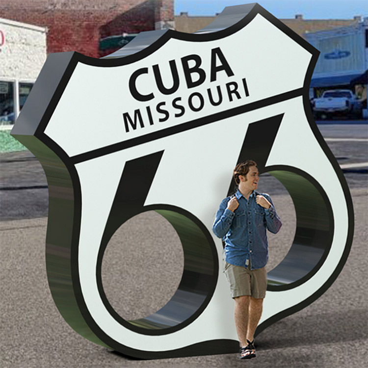 bigger than life sized Route 66 shield sign with man standing in front of it